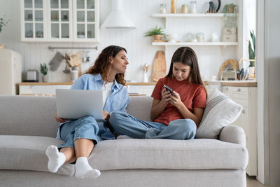 Mother using laptop while sitting on sofa at home