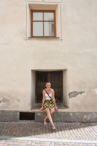 Full length of woman against house window