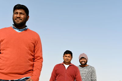 Portrait of friends with man standing against clear sky