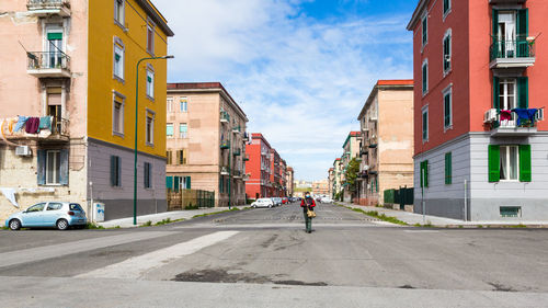 Road amidst buildings in city against sky