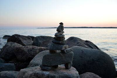 Stack of rocks at beach against sky during sunset