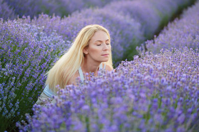 Portrait of young woman standing amidst purple flowering plants