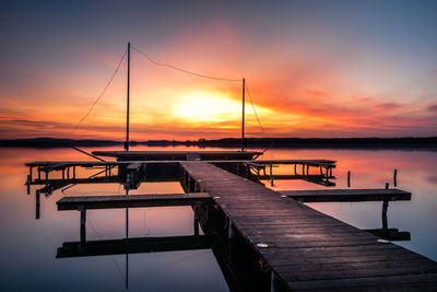 Pier on lake against sky during sunset