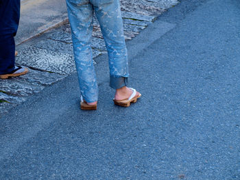 Low section of person wearing geta sandal while standing on road