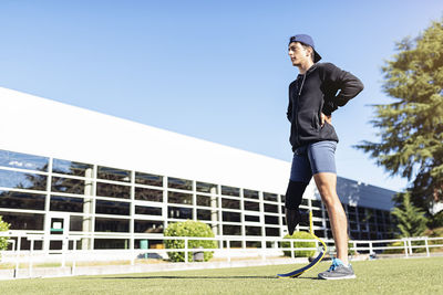 Low angle view of man with prosthetic leg standing in park during sunny day