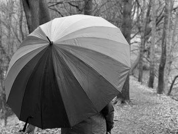 Rear view of person walking on wet road during rainy season