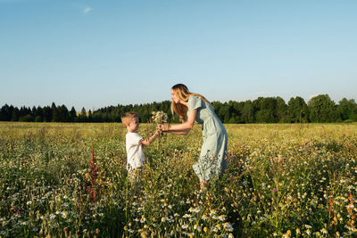 Portrait of smiling couple standing on field against clear sky