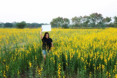 Woman standing on field with yellow flowers