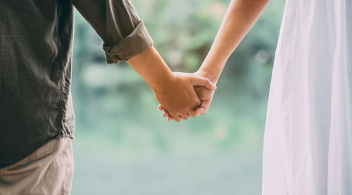 Midsection of couple holding hands