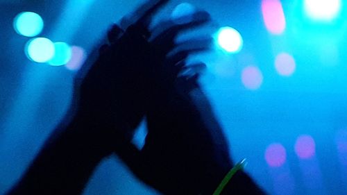 Defocused image of silhouette man on illuminated lights at night