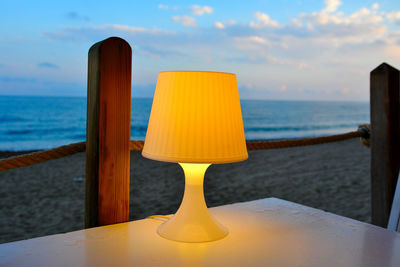 Close-up of yellow lamp over sea against sky