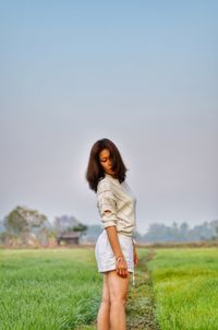 Woman standing on lawn against clear sky