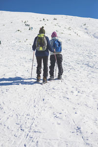 Rear view of couple skiing on snowcapped mountain