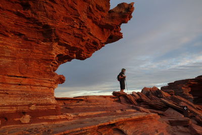 Man standing on rock formation against sky