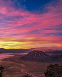 Scenic view of landscape against cloudy sky during sunset