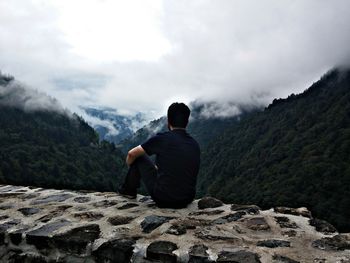 Rear view of man on mountain against cloudy sky