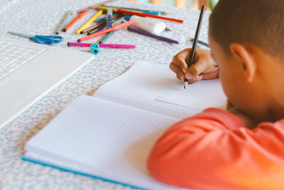 Midsection of boy reading book on table