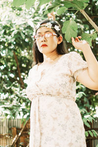 Portrait of woman standing by tree