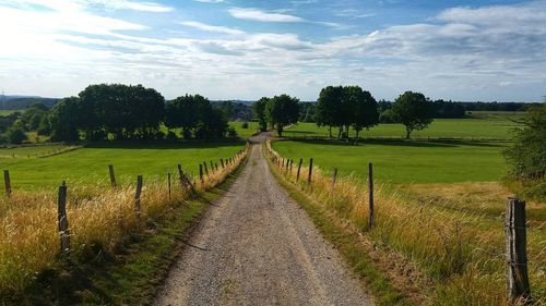 Road amidst field against sky