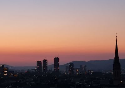 Silhouette of buildings in city during sunset