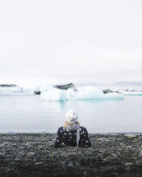 Man sitting in sea against sky