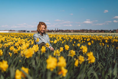 Girl sitting in a  yellow narcissus flowers field