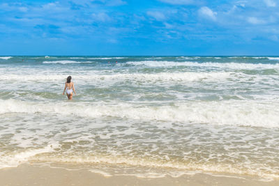 Rear view of woman on beach against sky