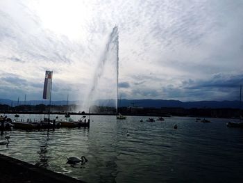 Boats in sea against cloudy sky