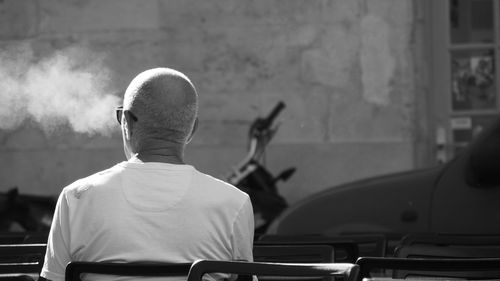 Rear view of man smoking while sitting on chair