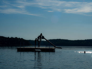 People in boat on lake against sky