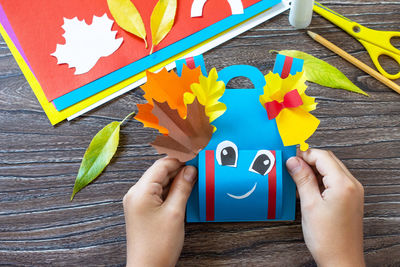 Low section of person holding multi colored painting on table