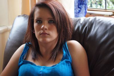 Close-up portrait of young woman sitting on sofa at home