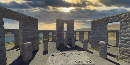 Wooden posts on beach against sky during sunset