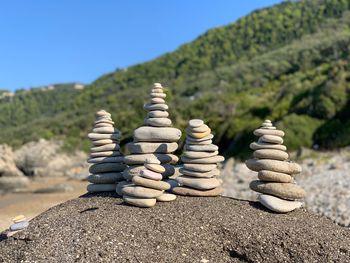 Stack of pebbles on rock against sky on sunny day