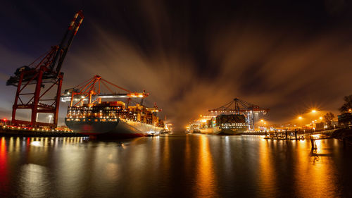 Container terminal with container ships, cranes and containers at night with beautiful clouds