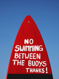 Low angle view of information sign against clear blue sky