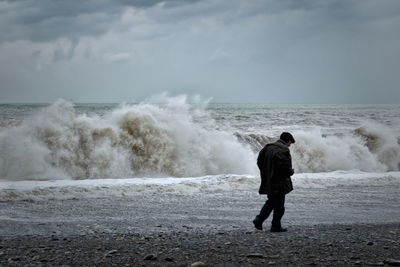 Full length of man standing on beach against sky