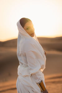 Young woman standing against sky during sunset