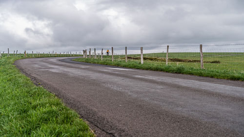 Road amidst field against sky
