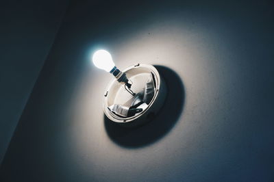 Close-up of illuminated light bulb against wall