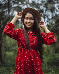 Portrait of smiling young woman standing against red tree