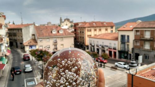 Cropped image of person holding crystal ball in city