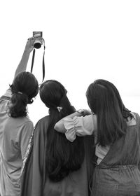 Rear view of female friends taking selfie