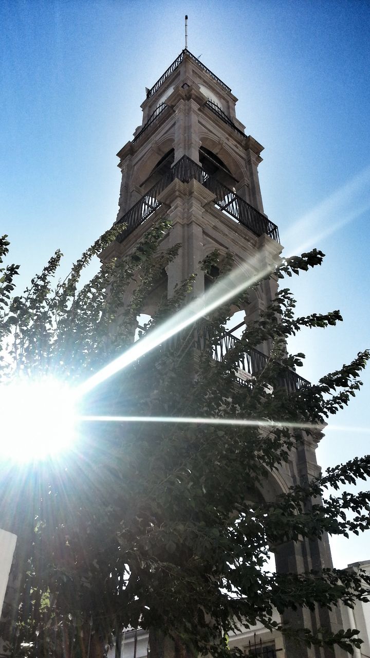 architecture, built structure, low angle view, sun, building exterior, sunbeam, famous place, sunlight, tree, tall - high, lens flare, tower, travel destinations, sky, religion, travel, blue, tourism, clear sky, capital cities