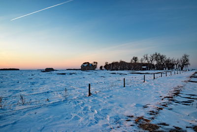 Scenic view of snow covered field against sky at sunset