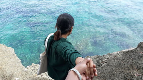 High angle view of man sitting on rock by sea