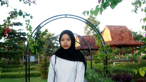 Portrait of beautiful young woman standing against plants