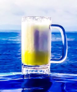 Close-up of drink on table against sea