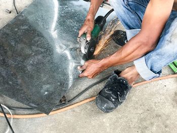 Low section of man cutting metal at workshop