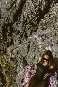High angle view of woman wearing sunglasses sitting on rock formation
